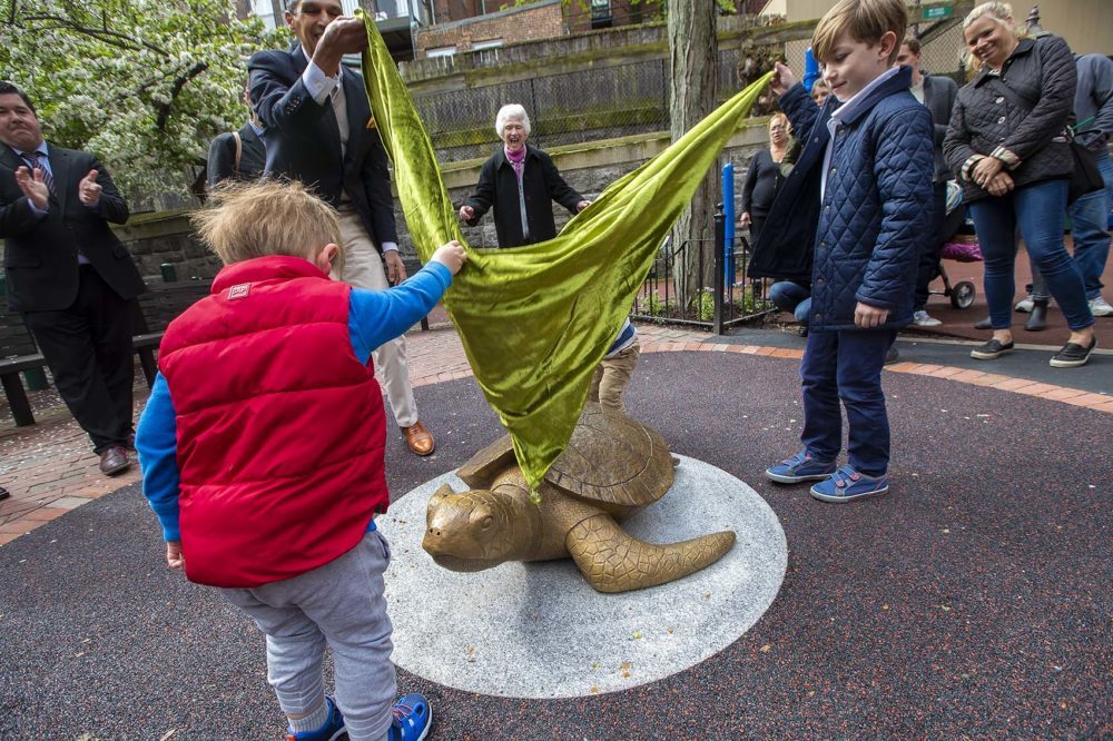 Sculptor Nancy Schön cheers from behind as children help unveil the &quot;Myrtle the Turtle&quot; sculpture in May. The sculpture is now being moved to prevent children climbing on it. (Jesse Costa/WBUR)