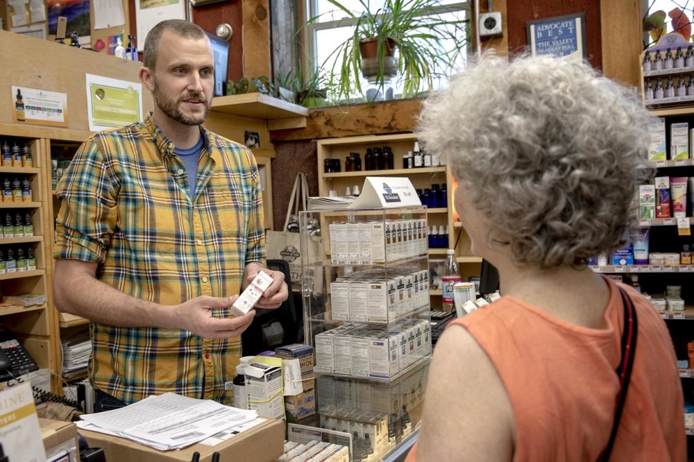 Nate Clifford, who owns Northampton's Cornucopia Natural Wellness Market with his wife, talks about a CBD product with a customer. (Robin Lubbock/WBUR)