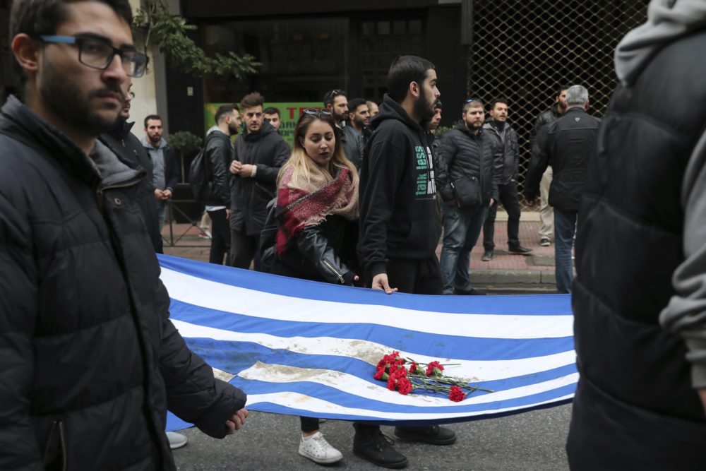 University students hold a blood-stained Greek flag from the deadly 1973 student uprising, in Athens, Nov. 17, 2018. That uprising was crushed by Greece's military junta, that ruled the country from 1967-74. (Yorgos Karahalis/AP)