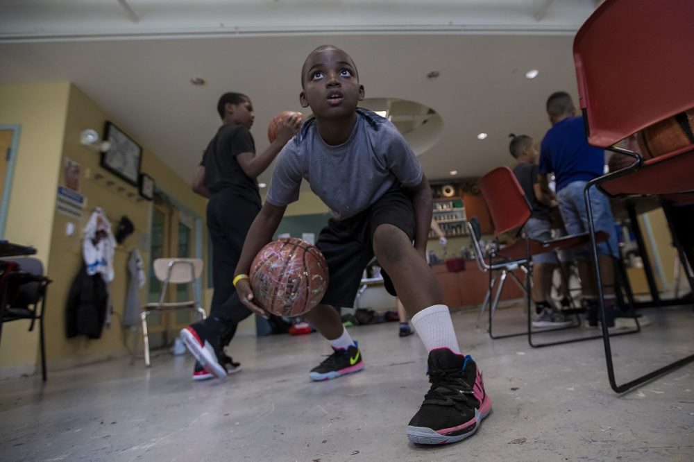 Nine-year-old Devin Miller bounces his decorated basketball between his legs during an old basketball decorating/collection event at the Yawkey Boys and Girls Club in Roxbury. (Jesse Costa/WBUR)