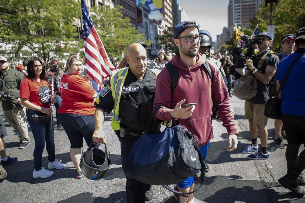 A counter-protester is escorted by a Boston police officer during the “Straight Pride” parade. (Jesse Costa/WBUR)