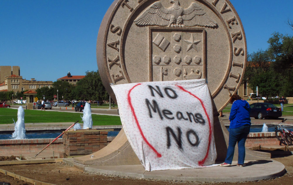 In this 2014 photo, a student helps drape a bed sheet with the message &quot;No Means No&quot; over the university's seal at the Lubbock, Texas campus in a demonstration against sexual violence on campus. (Betsy Blaney/AP)