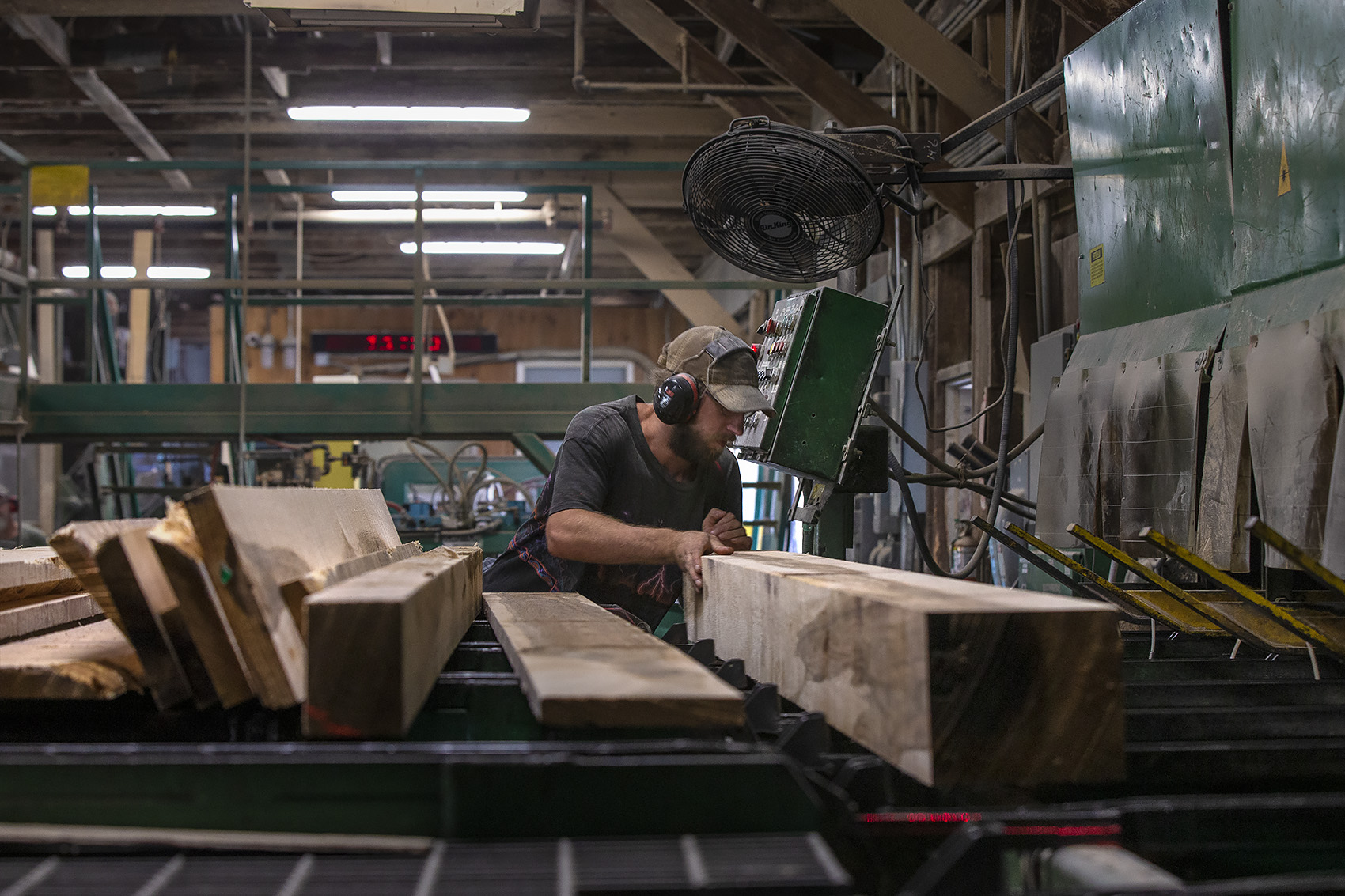An employee inspects oak boards before they are sorted at Allard Lumber in Brattleboro, Vermont. (Jesse Costa/WBUR)
