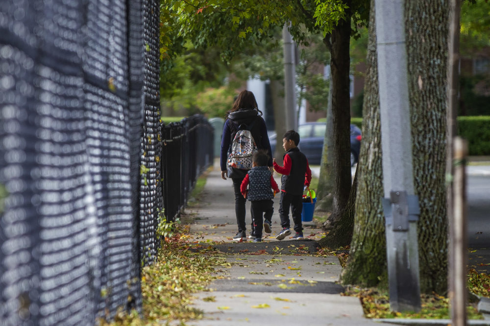 A mother walks with her two children along Still Street on their way to the park at Winthrop Square in Brookline. (Jesse Costa/WBUR)