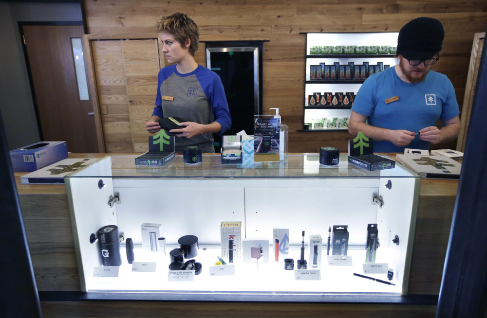 Patient service associates Savannah Stuitje, left, and Josh Hirst, right, stand at a counter that features a display of vape dispensers that could be used for legal recreational cannabis, at New England Treatment Access medical marijuana dispensary (Steven Senne/AP File Photo)
