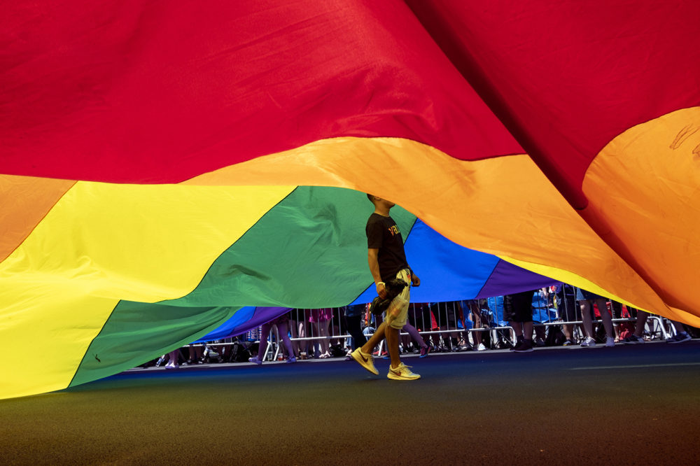 A participant walks under a large rainbow flag during the LBGTQ Pride march Sunday, June 30, 2019, in New York. (Craig Ruttle/AP)
