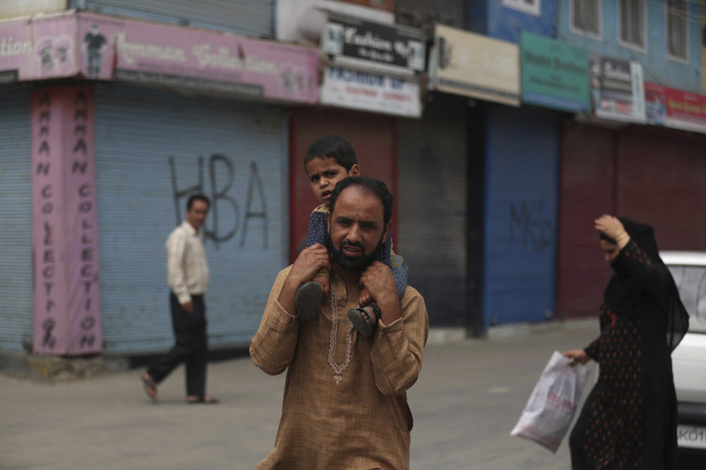 A Kashmiri man carries a child on his shoulders at a closed market area in Srinagar, Indian controlled Kashmir, Saturday, Aug. 31, 2019. New Delhi downgraded Muslim-majority Kashmir's autonomy on Aug. 5 and imposed a security clampdown to prevent any violent response. (AP Photo/Mukhtar Khan)