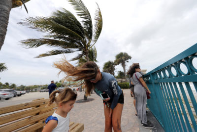 Kristen Davis watches the high surf from a boardwalk overlooking the Atlantic Ocean with her daughter Addie Davis 4, as winds from Hurricane Dorian blow the fronds of a palm tree palm tree, in Vero Beach, Fla., Monday, Sept. 2, 2019. (Gerald Herbert/AP)