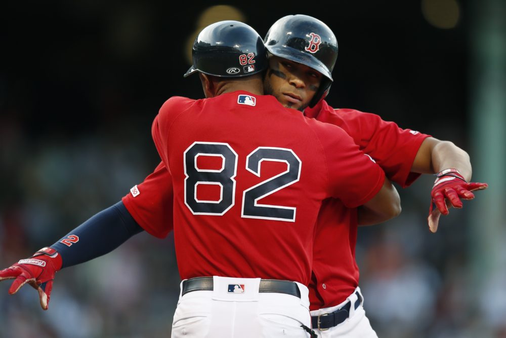 First base coach Tom Goodwin (82) hugs Xander Bogaerts after Bogaerts' RBI single during the seventh inning of the game. (Michael Dwyer/AP)