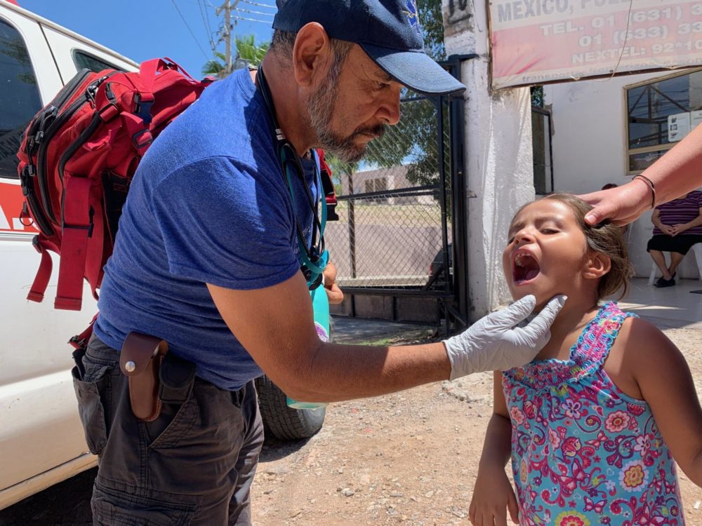 Pancho Olachea, a registered nurse in Mexico, examines a young girl's teeth. (Michel Marizco/KJZZ)