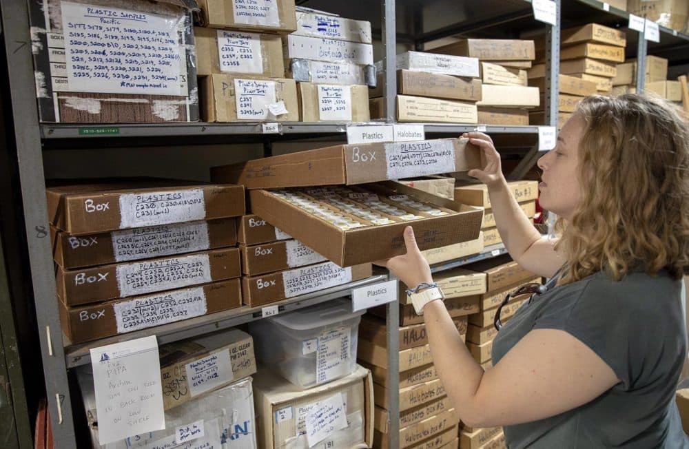 Jessica Donohue, a senior research assistant at Sea Education Association, looks into a box filled with vials of plastic material filtered from the ocean. (Robin Lubbock/WBUR)