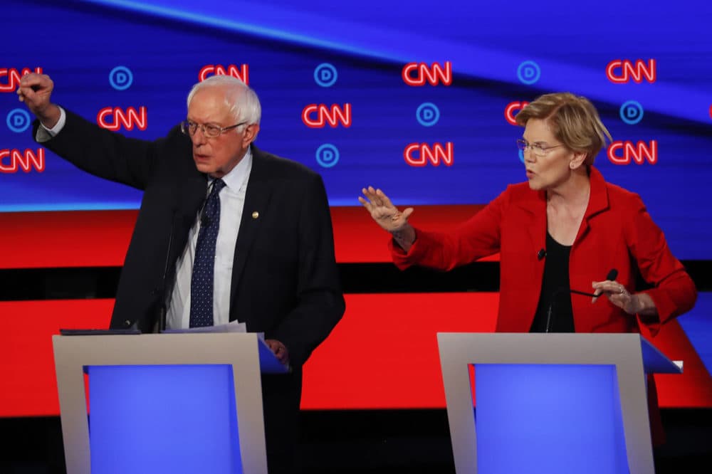 A CBS poll has Sen. Bernie Sanders, I-Vt., leading in both Iowa and New Hampshire ahead of next month's Democratic presidential primaries while Sen. Elizabeth Warren, D-Mass., lags behind. Here, Sanders and Warren talk during in the first of two Democratic presidential primary debates hosted by CNN last July. (Paul Sancya/AP)