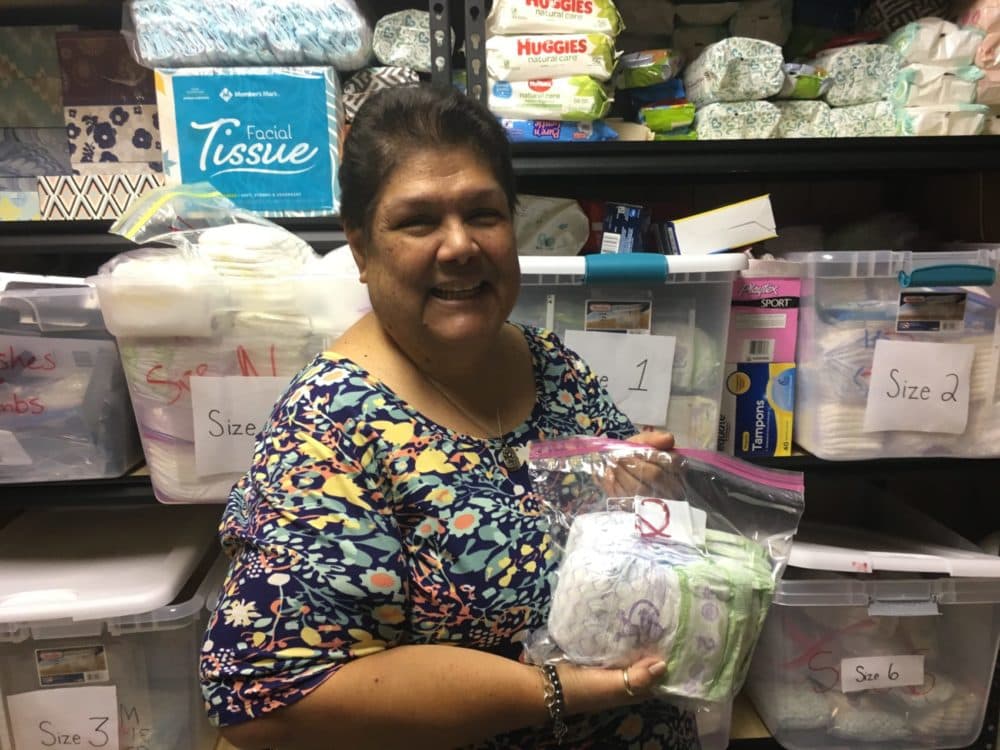 Marianela Watson, of Good Neighbor Settlement House, smiles and shows off a bag of donated diapers. (Yasmin Amer/WBUR)