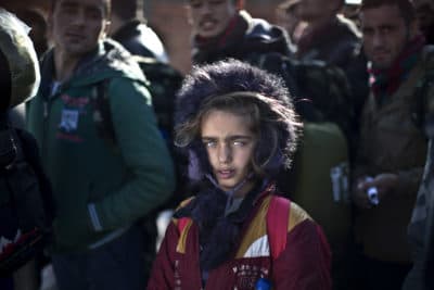 In this Dec. 5, 2015 file photo, Yazidi refugee Salma Bakir, 9, from Iraq, waits with her family to be permitted by Macedonian police to board a train heading to the Serbian border, near the southern Macedonian town of Gevgelija. (Muhammed Muheisen/AP)