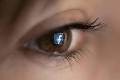 An illustration picture taken on March 22, 2018 in Paris shows a close-up of the Facebook logo in the eye of an AFP staff member posing while she looks at a flipped logo of Facebook. (CHRISTOPHE SIMON/AFP via Getty Images)
