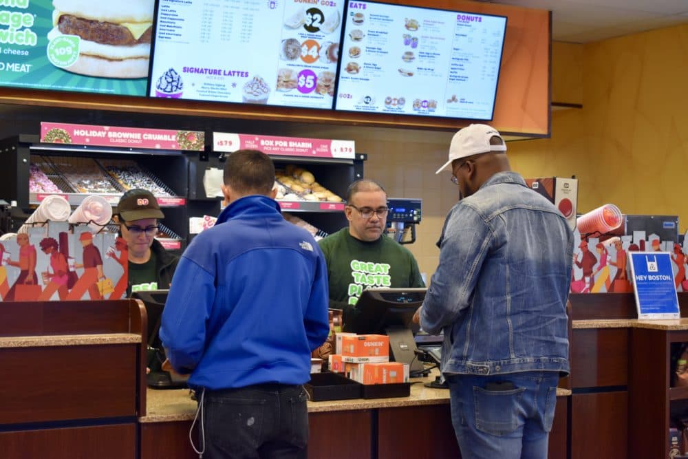 At the Dunkin' on North Beacon Street in Brighton, Nehemiah Campos, right, and another employee take orders. (Meghan B. Kelly/WBUR)