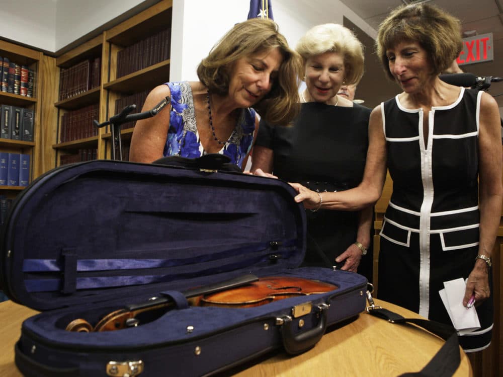 The Totenberg sisters — Amy (from left), Nina and Jill — see their father's stolen Stradivarius for the first time in 35 years at the U.S. attorney's office in New York City on Thursday. (Lydia Thompson/NPR)