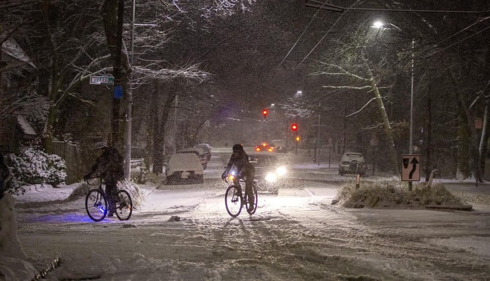 Bicyclists make a turn off a snowy Mount Auburn Street on Sunday evening. (Robin Lubbock/WBUR)
