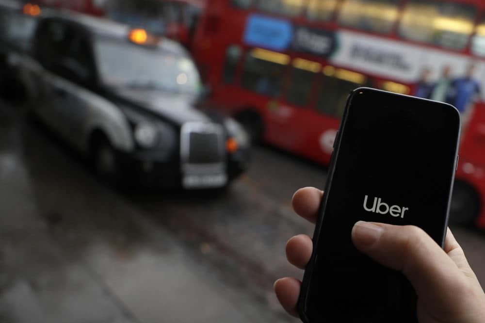 In this posed picture, the Uber app is opened on a mobile phone, backdropped by other transport services in London, Monday, Nov. 25, 2019. (Kirsty Wigglesworth/AP)