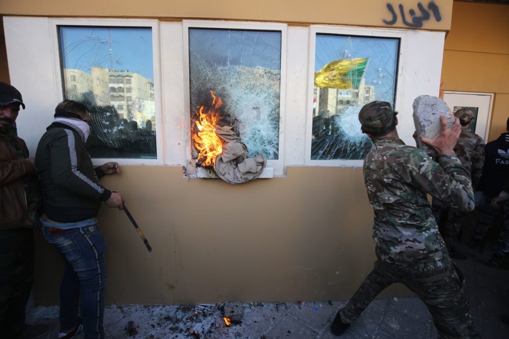 Members the Hashed al-Shaabi, a mostly Shiite network of local armed groups trained and armed by powerful neighbour Iran, smash the bullet-proof glass of the US embassy's windows in Baghdad. (Photo by Ahmad Al-Rubaye/AFP via Getty Images)