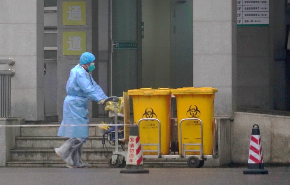 Staff move bio-waste containers past the entrance of the Wuhan Medical Treatment Center, where some infected with a new virus are being treated, in Wuhan, China on Jan. 22. (Dake Kang/AP)