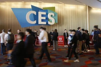 Attendees head to the convention floor on the first day of the Consumer Electronics Show. A CES banner hangs on the wall in the background.