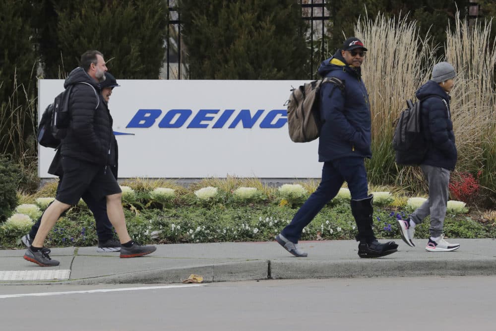 Workers walk past a Boeing Co. sign as they leave the factory where the company's 737 Max airplanes are built, Dec. 17, 2019. As Boeing prepares to shutter much of the huge factory near Seattle that builds the grounded 737 Max jet, the economic hit is reverberating across the United States. (Ted S. Warren/AP)