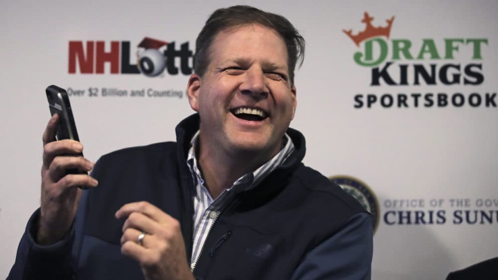 New Hampshire Gov. Chris Sununu smiled after using the DraftKings mobile app to place a sports bet in Manchester, N.H., on Dec. 30, 2019. New Hampshire has partnered with DraftKings to operate a sportsbook in the state. (Charles Krupa/AP)