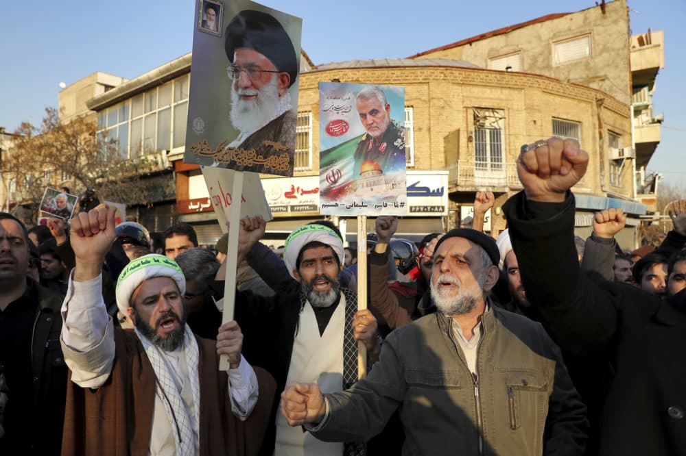 Hardline protesters chant slogans while holding up a poster of Gen. Qassem Soleimani and Supreme Leader Ayatollah Ali Khamenei, during a demonstration in front of the British Embassy in Tehran, Iran, Sunday, Jan. 12, 2020. (Ebrahim Noroozi/AP)