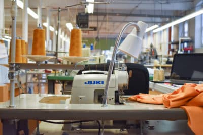 A sewing station complete with an industrial machine and large spools of thread at a clothing manufacturer in Fall River, Massachusetts. (Allison Hagan/Here & Now)