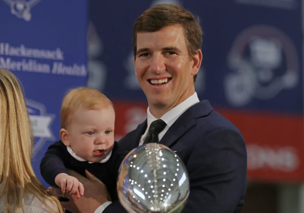 New York Giants quarterback Eli Manning holds his son after announcing his retirement on Friday. (Adam Hunger/AP)