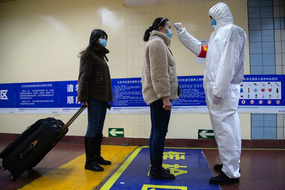 A health worker checks the temperature of women entering the subway on January 26, 2020 in Beijing, China. (Betsy Joles/Getty Images)