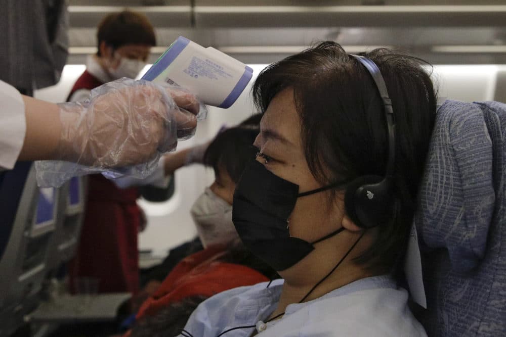 Stewardesses take temperatures of passengers as a preventive measure for the coronavirus on an Air China flight from Melbourne to Beijing before it land at Beijing Capital International Airport in China on Tuesday. (Andy Wong/AP)