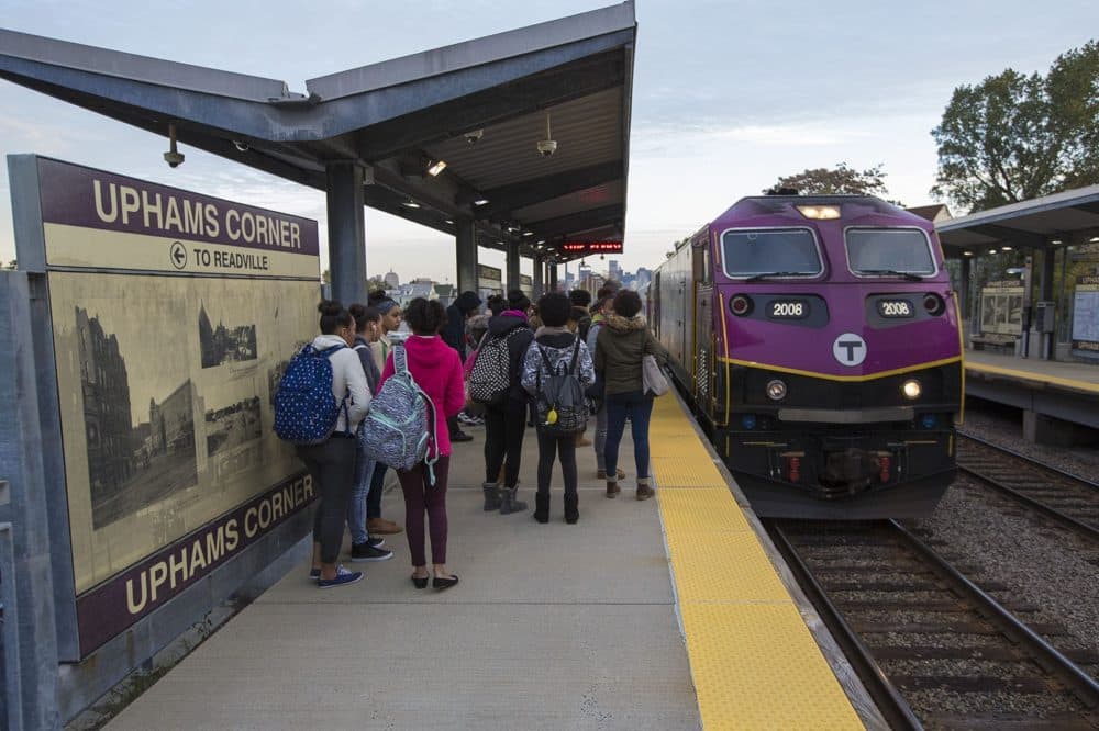 A large group of students on their way to Jeremiah Burke High School wait as the Fairmount Line Commuter Rail train pulls into Uphams Corner Station in early morning. (Jesse Costa/WBUR)