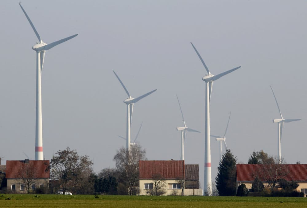 Wind turbines stand behind houses of the village of Feldheim near Berlin, Germany. (Michael Sohn/AP)