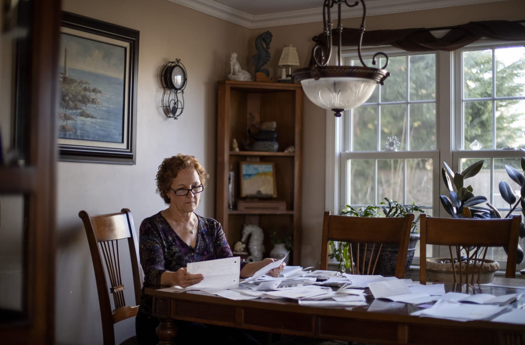 Janet Uhlar sits at her dining room table with letters and photos she received through her correspondence with imprisoned Boston organized crime boss James &quot;Whitey&quot; Bulger, Jan. 31, 2020, in Eastham, Mass. (David Goldman/AP)