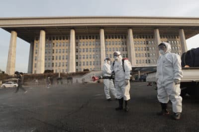 Workers wearing protective suits spray disinfectant as a precaution against the coronavirus at the National Assembly in Seoul, South Korea, Monday, Feb. 24, 2020. (Ahn Young-joon/AP)