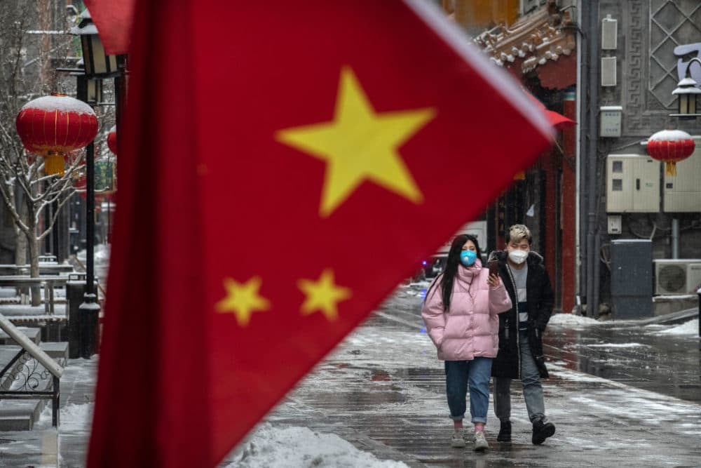 A Chinese couple wear protective masks as they walk during a snowfall in an empty and shuttered commercial street on February 5, 2020 in Beijing, China. (Kevin Frayer/Getty Images)