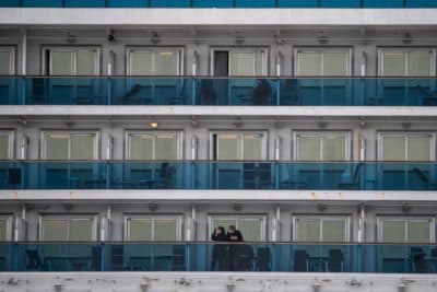 Passengers wearing face masks look out from their cabin on the Diamond Princess cruise ship in quarantine due to fears of COVID-19. (Philip Fong/AFP/Getty Images)