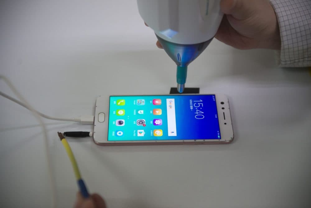 A smartphone receives electrical shocks at the testing facility of the Oppo factory in Dongguan, China. (Nicolas Asfouri/AFP via Getty Images)