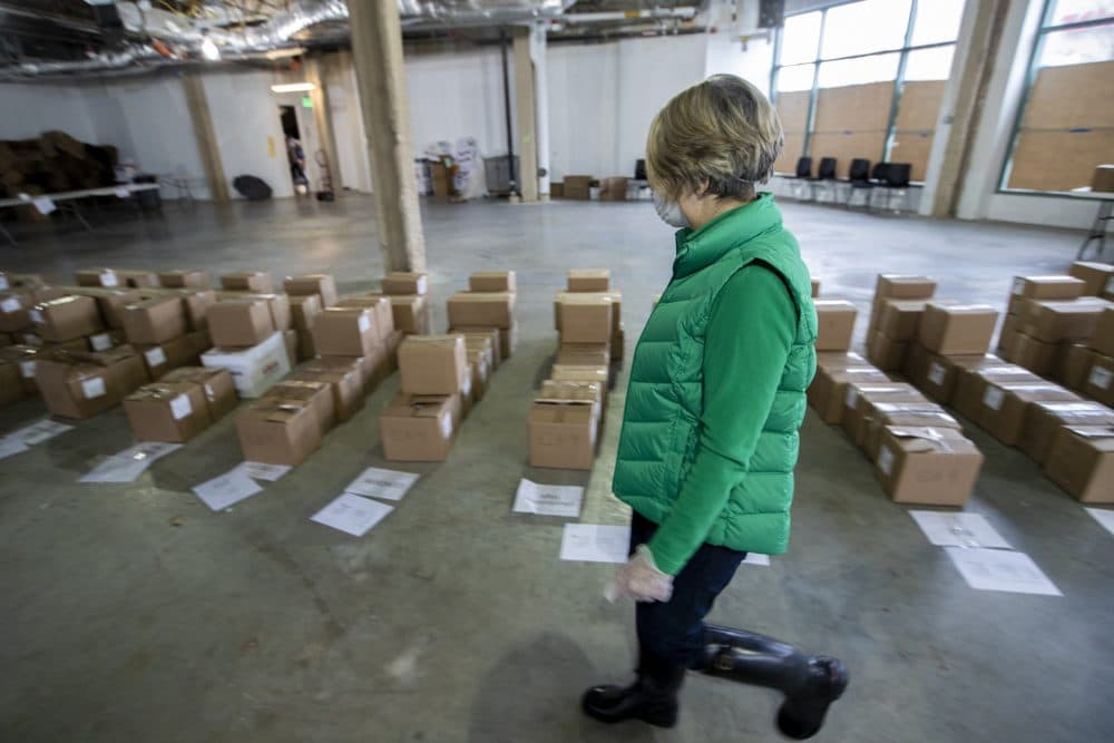 A worker examines boxed-up course material for each Boston Public Schools student to resume their coursework remotely with the Chomebook they will receive. (Jesse Costa/WBUR)