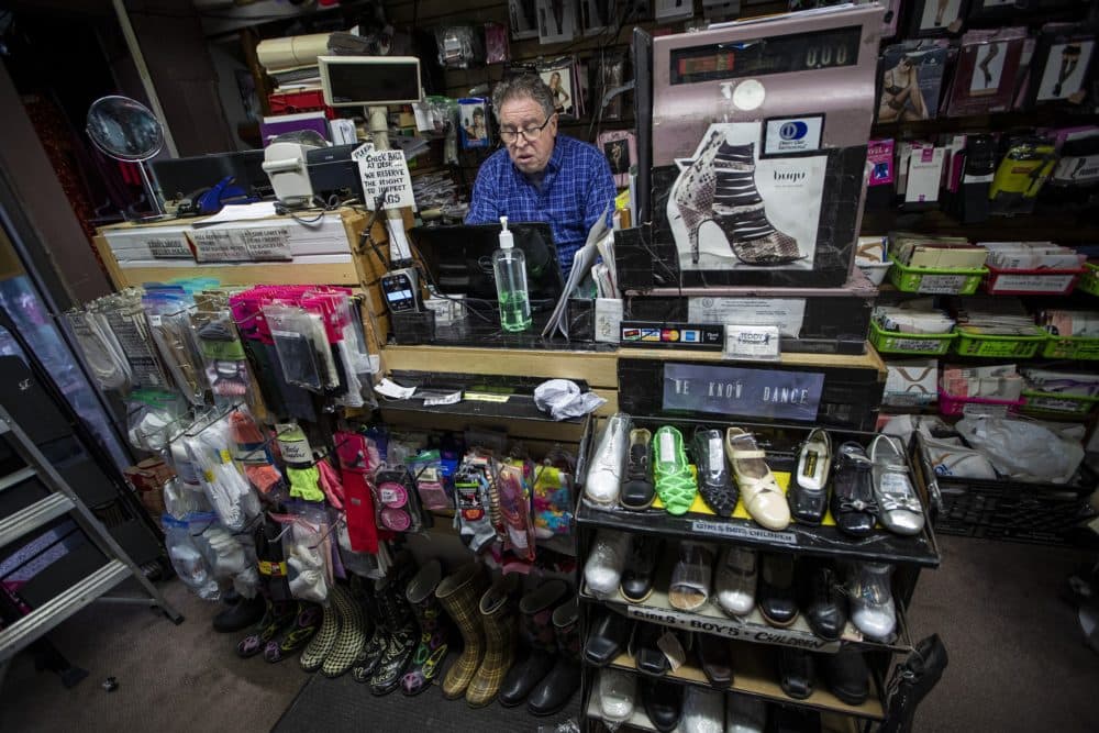 Teddy Shoes owner Steven Adelson sits behind the counter of his store working on a GoFundMe page. He hopes with the combination of online sales and donations he receives, he will be able to keep his business. (Jesse Costa/WBUR)