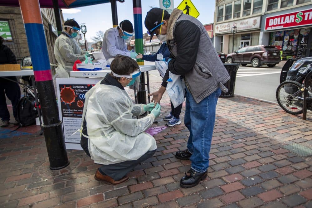 Data from Partners HealthCare shows that about 1 percent of asymptomatic patients at Partners hospitals tested positive for the coronavirus. Dr. John Iafrate, a pathologist at Massachusetts General Hospital, takes a blood sample from a Chelsea resident at a pop-up testing facility in Bellingham Square. (Jesse Costa/WBUR)