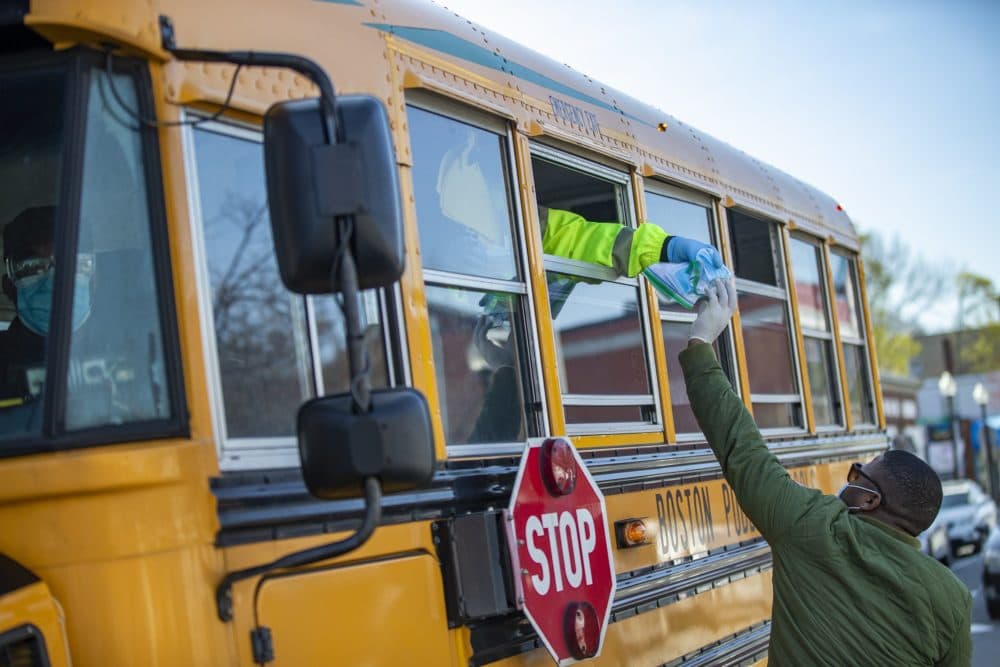 Winston Bodrick passes out a face mask and hand sanitizer to workers on a school bus making deliveries in Codman Square. Members of the Omega Psi Phi’s Eta Phi Chapter plan to distribute some 50,000 free face masks to people most in need -- including seniors -- in the neighborhoods of Roxbury, Dorchester, Mattapan and Jamaica Plain. (Jesse Costa/WBUR)