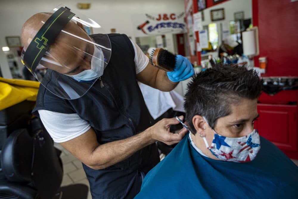 Leuris Luna gives a haircut to a customer at J&C Barber Shop in Roxbury, the first day of reopening during the COVID-19 pandemic. (Jesse Costa/WBUR)