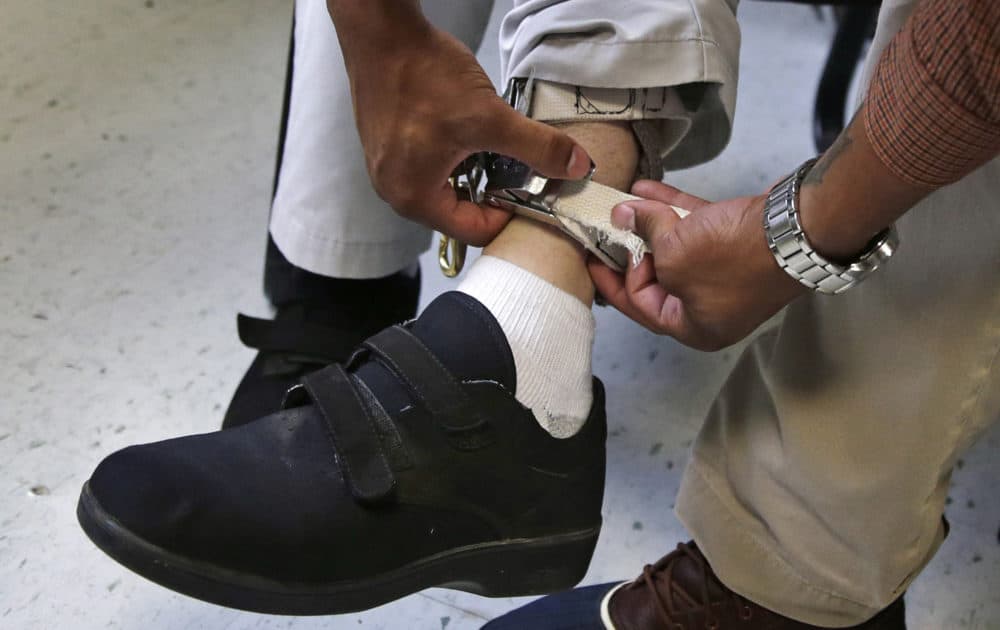 In this Aug. 2014 file photo, a therapist checks the ankle strap of an electrical shocking device on a student during an exercise program at the Judge Rotenberg Educational Center in Canton, Mass. (Charles Krupa/AP)