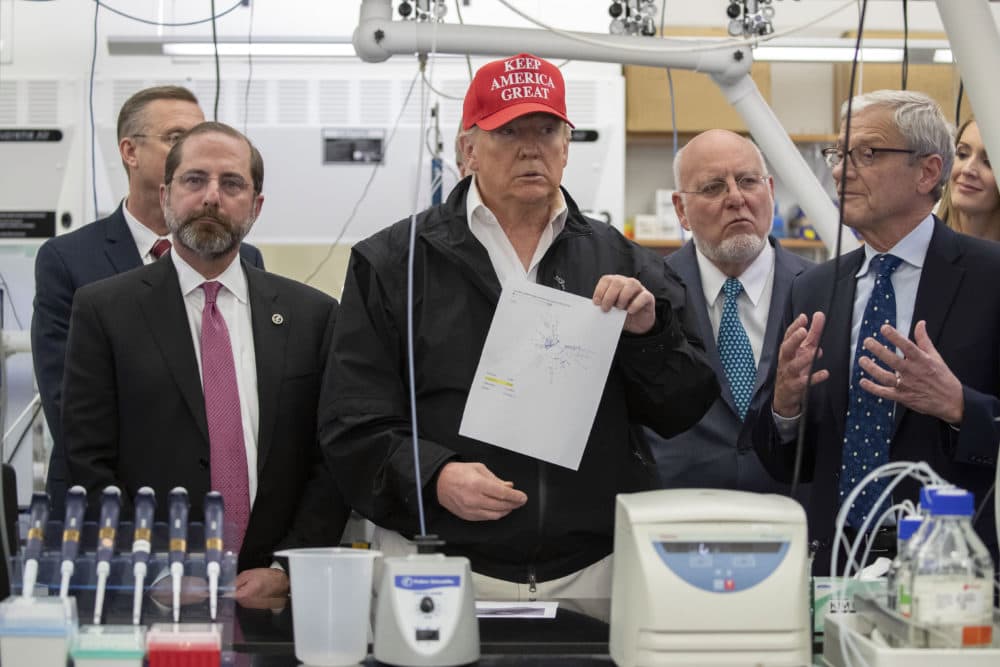 President Donald Trump holds up a picture as he listens during a meeting with Health and Human Services Secretary Alex Azar, left, Associate Director for Laboratory Science and Safety Steve Monroe, and Centers for Disease Control and Prevention Director Dr. Robert Redfield, about the coronavirus at the Centers for Disease Control and Prevention, Friday, March 6, 2020 in Atlanta. (Alex Brandon/AP)