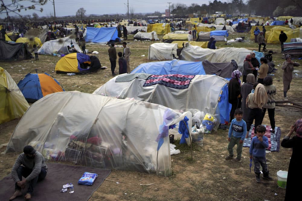 Migrants stand by tents in a camp set up near the Turkish-Greek border in Pazarkule, Edirne region, Turkey, Tuesday, March 10, 2020. (Ismail Coskun/IHA via AP)