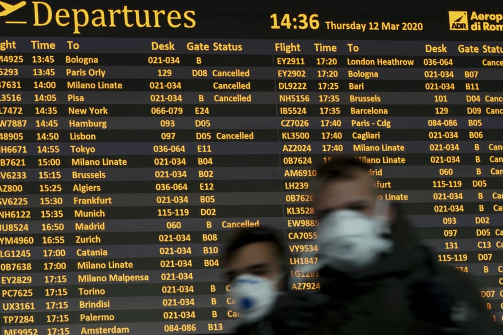 People walk by a departures monitor at the Rome Leonardo da Vinci international airport, Thursday, March 12, 2020. (Andrew Medichini/AP Photo)