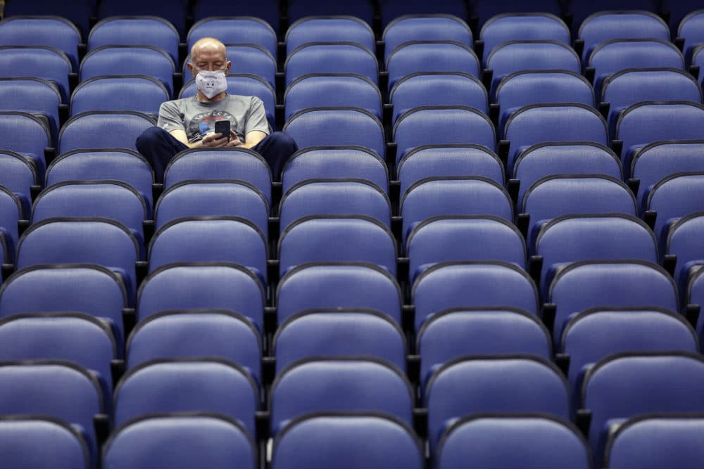 A fan sits in an empty arena after the NCAA canceled the Atlantic Coast Conference tournament on Thursday. (Ben McKeown/AP)
